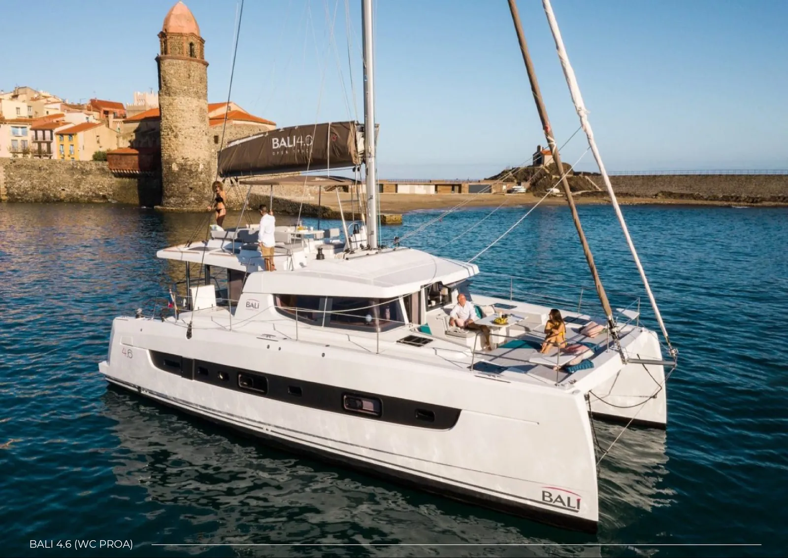 Guests relaxing on the foredeck of a Bali 4.6 off a Mediterranean old town